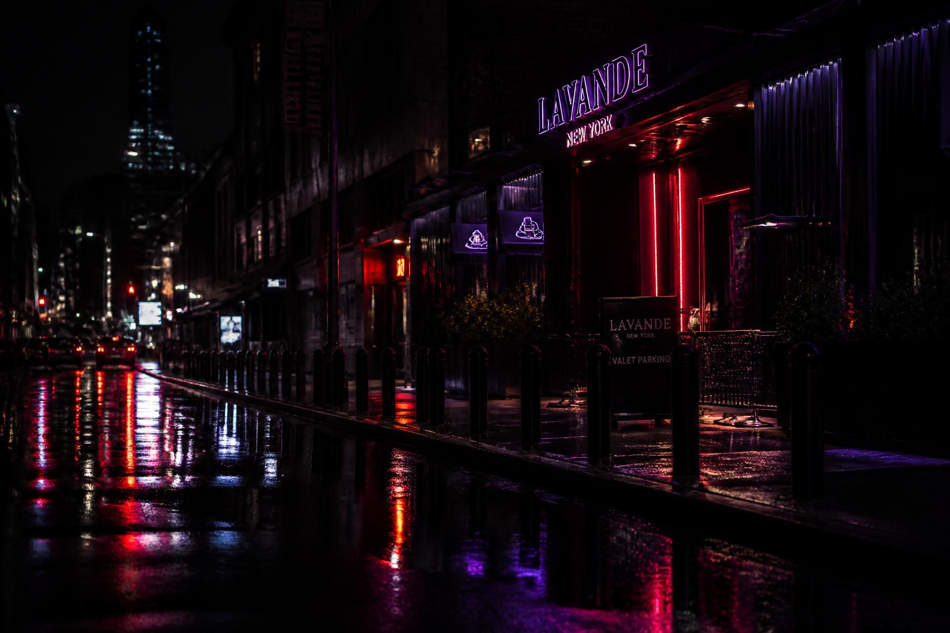 Rain-slicked New York street glowing with neon after midnight